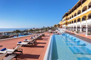 un hotel con piscina e tavoli e sedie di Occidental Jandía Royal Level - Adults Only a Morro del Jable