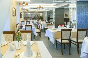 a dining room with white tables and chairs at Abri Hotel in Dnipro
