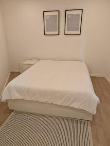a white bed in a bedroom with two pictures on the wall at Casa do Picadeiro in Elvas
