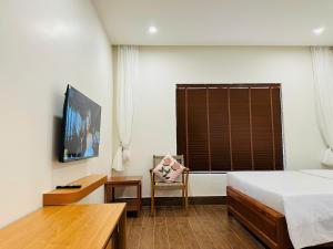 a bedroom with a bed and a chair and a television at Núp Gió Cottages in Ấp Mỹ Hải