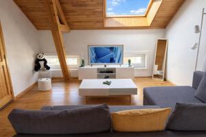 a living room with a couch and a tv at Loft Chaleureux - Le Chalet Montois in Mons