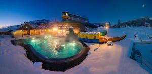 a house with a swimming pool in the snow at Julius Appartements & Zimmer in Wagrain