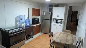 a kitchen with a table and a stove and refrigerator at Residencia cercana ENGIE in Tocopilla