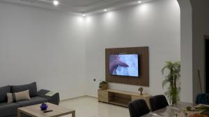 a living room with a couch and a tv on a wall at Luxury Terrace Apartment in Al Hoceïma