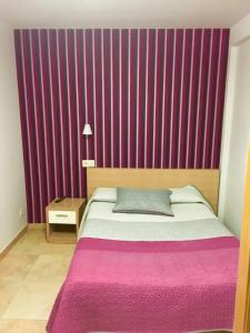 a bedroom with a bed with a purple wall at Hostal La Cortijana in Logroño
