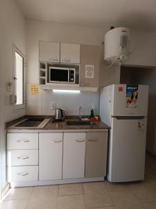 eine Küche mit einem weißen Kühlschrank und einer Mikrowelle in der Unterkunft SUEÑOS DE TERMAS in Chajarí