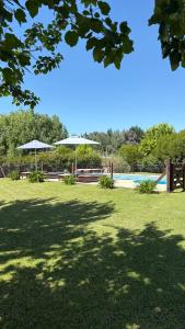 a park with two umbrellas and a swimming pool at Aroma de campo in Chascomús