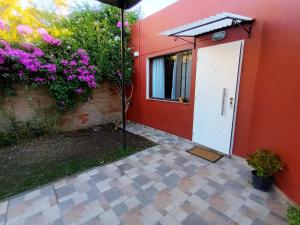 a red house with a white door and flowers at Departamento CRIMAR in Viedma