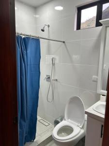 a bathroom with a toilet and a shower with a blue shower curtain at Boutique Exclusive Stay in Baños +30 photos