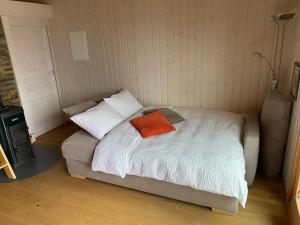 a bed with an orange pillow on top of it at "La Romantica" Superior Chalet Rifugio Nel Bosco in Astano