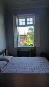 a bedroom with a white bed and a window at Vila Santa Eulália Hostel in Pelotas