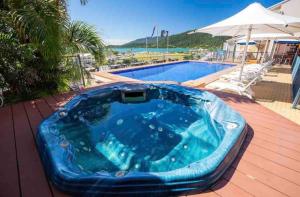 a blue tub sitting on a deck next to a swimming pool at Heavenly Views in Airlie Beach