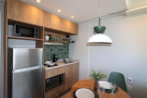 a kitchen with a table and a stainless steel refrigerator at MOOD Modern Studio, Central Parque in Porto Alegre