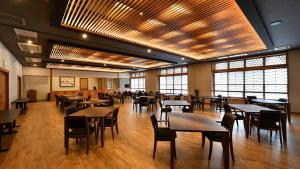 a dining room with tables and chairs and windows at Hinanoyado Chitose in Tokamachi