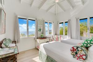 a white bedroom with windows and a bed at Villa Serena Water Island in Water Island +146 photos