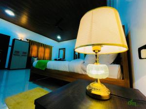 a lamp on a table in a bedroom with a bed at Om Hotel in Unawatuna