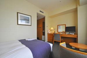 a hotel room with a bed and a desk with a computer at ホテルベルクラシック北見 in Kitami