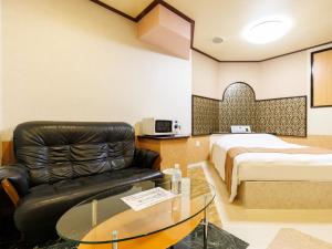 a hotel room with a couch and a bed at Tabist ONSEN MOTEL272 in Naka-shibetsu