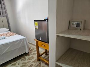 a small room with a small refrigerator and a bed at Caribbean Airport Hotel in Cartagena de Indias