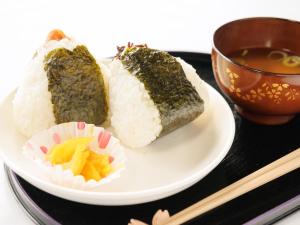 two pieces of sushi on a plate with a cup of tea at Tabist ONSEN MOTEL272 in Naka-shibetsu