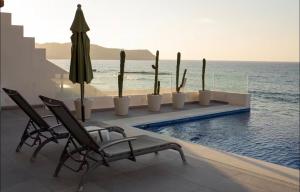 a swimming pool with chairs and cacti and the ocean at Apartamento en Punta Mita in Higuera Blanca +5 photos