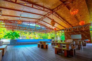 a restaurant with wooden tables and a blue couch at Arenal Backpackers Resort in Fortuna