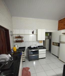 a kitchen with black counter tops and white appliances at Chácara Paraíso do Mar - Araçagi in São José de Ribamar