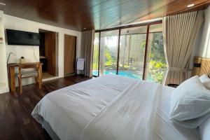 a bedroom with a white bed and a large window at Novella Tagaytay in Tagaytay