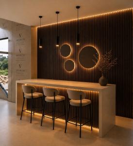 a bar with three stools and a counter with lights at Casa del Rosa in Kafr ‘Ubaydā