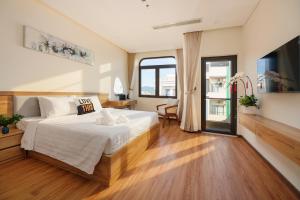a bedroom with a bed and a large window at Cossy Home by BRIO in Danang