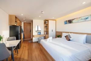 a bedroom with a large white bed and a desk at Cossy Home by BRIO in Danang +30 photos