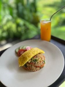 a sandwich on a plate with a glass of orange juice at Abian view house in Sidemen +17 photos