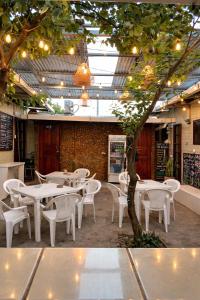 a restaurant with white tables and chairs and a tree at Hostal Los Chamos in San Juan del Sur