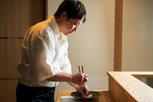 a man preparing food on a plate on a table at Kappo Ryokan Yumesaki in Beppu