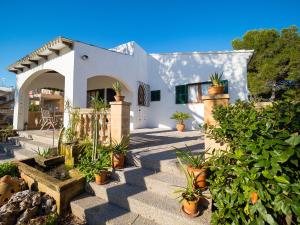 a white house with potted plants in front of it at Son Serra II in Son Serra de Marina