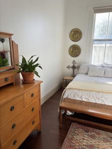 a bedroom with a bed and a dresser with a plant on it at Timeless Villa on Parore in Dargaville