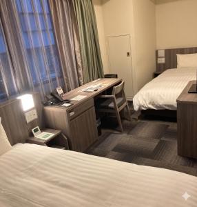a hotel room with a desk and two beds at Dormy Inn Korakuen in Tokyo +94 photos