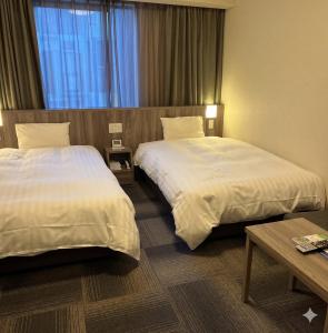 a hotel room with two beds and a table at Dormy Inn Korakuen in Tokyo
