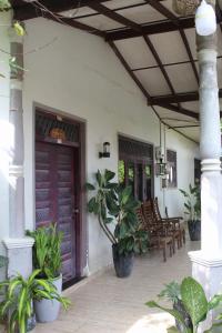 a porch of a house with a wooden door and chairs at surfing lion villa kudawella in Mawella