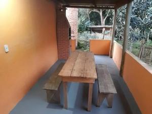 a wooden table on a porch with a bench at Chalé das águas in Cunha