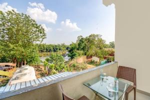a balcony with a glass table and a view of a river at Atithi Comforts in Kushālnagar