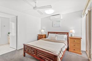 a white bedroom with a bed and a dresser and a ceiling at The Crabpot in Airlie Beach