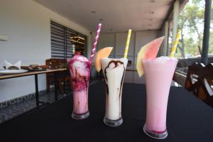 three different colored drinks in vases on a table at Atithi Comforts in Kushālnagar