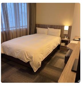 a hotel room with a bed with white sheets and a window at Dormy Inn Korakuen in Tokyo