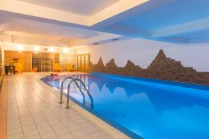 a large swimming pool with blue water in a building at udanypobyt Apartament z Basenem in Zakopane