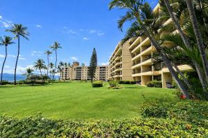 a large apartment building with palm trees and a lawn at Oceanfront Artist Condo Panoramic Maui Sunsets in Kihei +49 photos