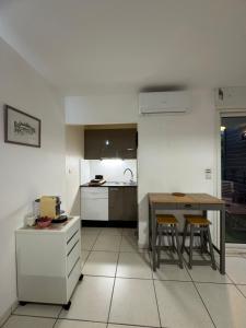 a kitchen with a table and two stools in it at Prana Lodge Saint Gilles les Bains 800 m de la plage in Saint-Gilles-les-Bains