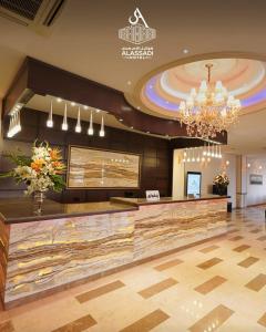 a lobby with a reception desk and a chandelier at Al-Assadi Hotel in Erbil