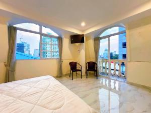 a bedroom with a bed and two chairs and windows at A Z Hotel Phnom Penh in Phnom Penh +13 photos