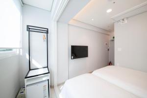 a small bedroom with two beds and a tv at K-Grand Hostel Sinchon in Seoul